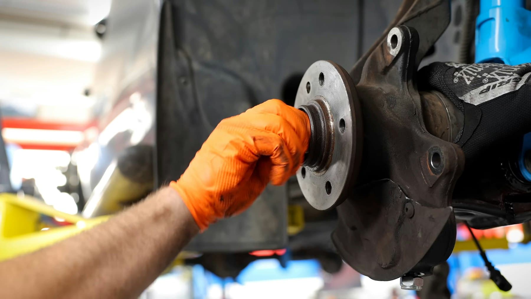 A brake rotor held in a gloved hand during a repair