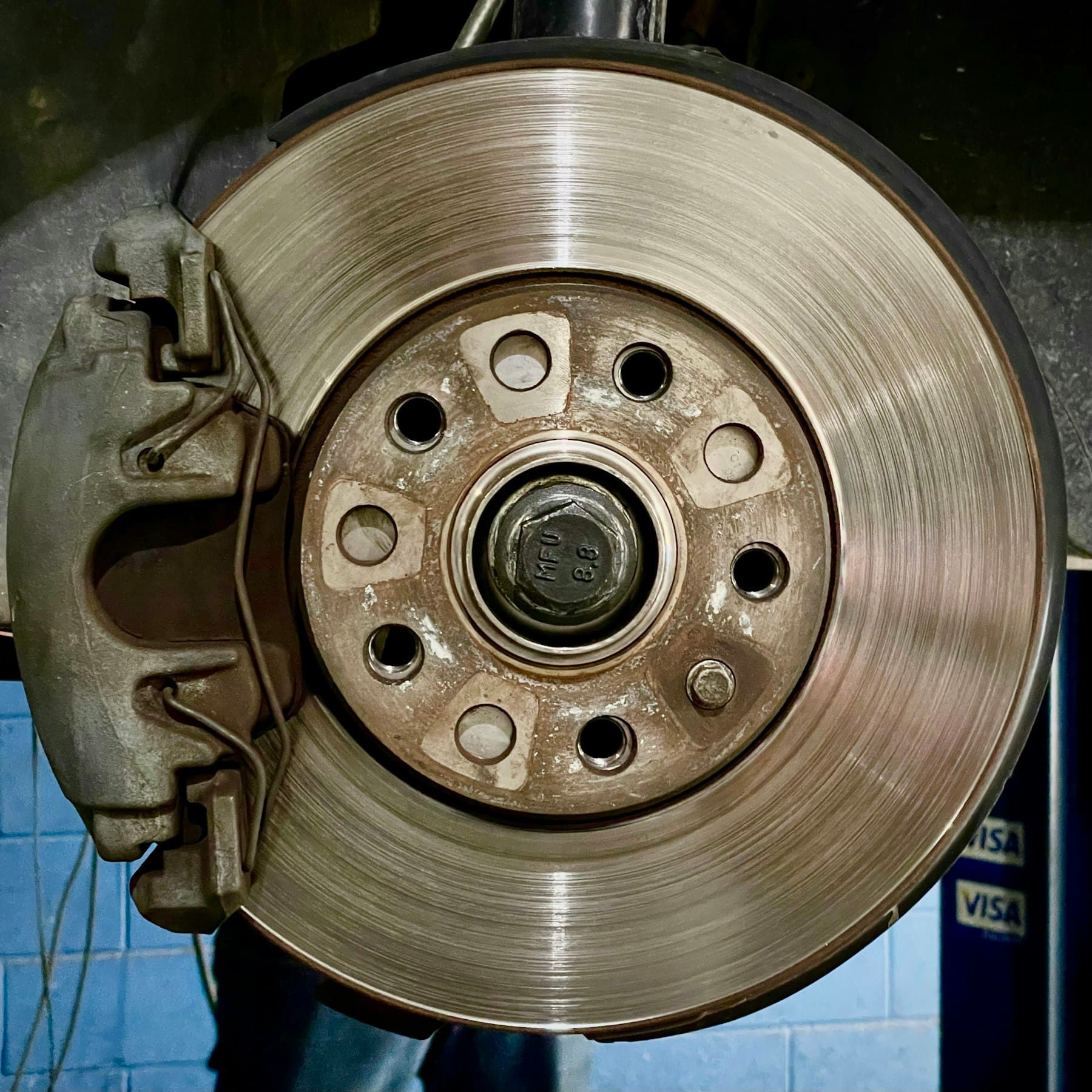 A worn brake rotor and caliper still fitted to a wheel hub