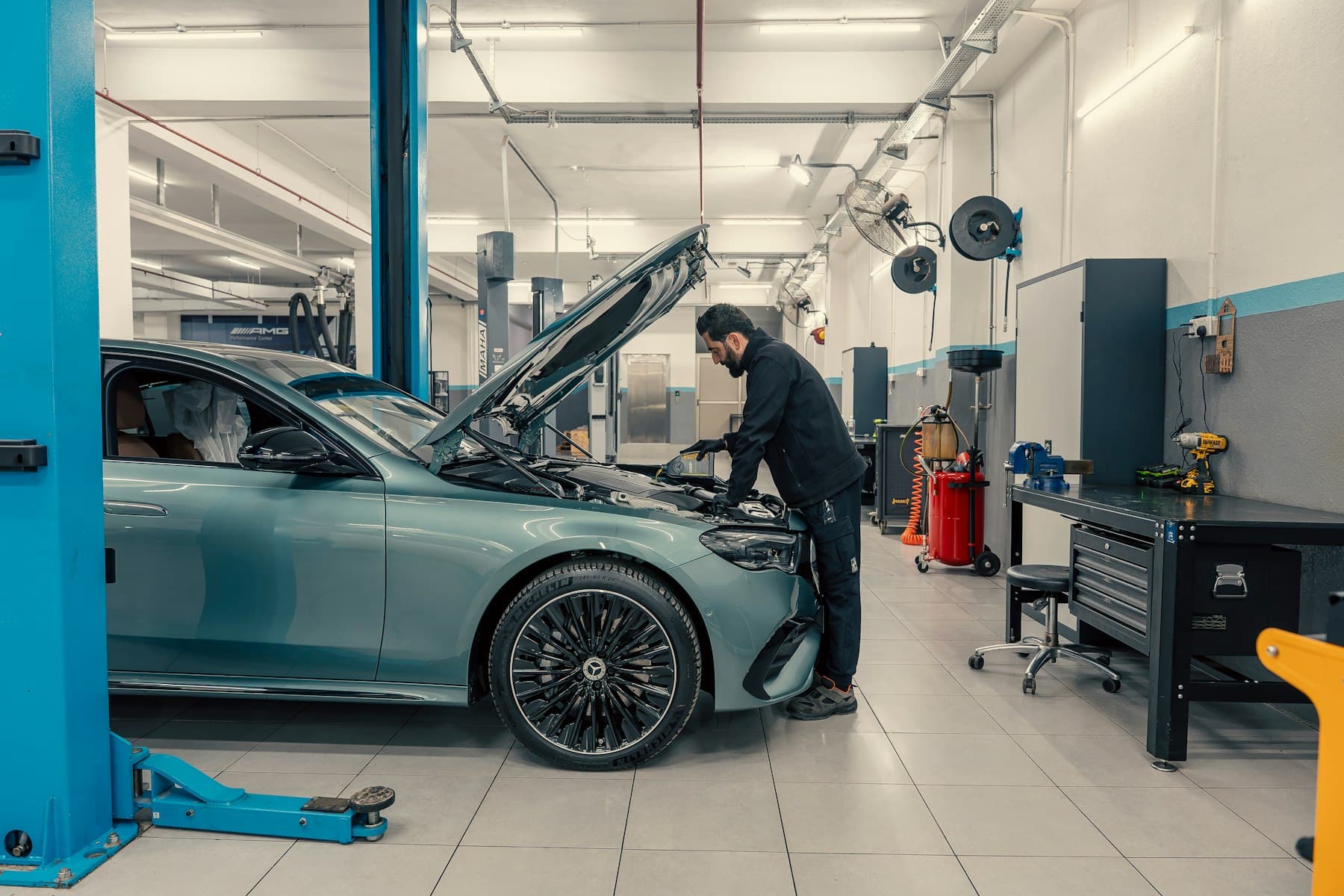 A technician working on a car raised on a hoist in a workshop